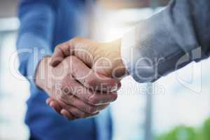 Forming a new merger. Closeup shot of a two unrecognizable businessmen shaking hands in an office.