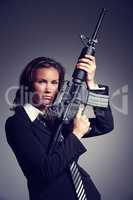 Shes a merciless manager. A young businesswoman wearing a suit and tie holding a rifle.