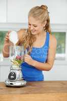 Creating a fantastic smoothie. Attractive young woman making a fruit smoothie.