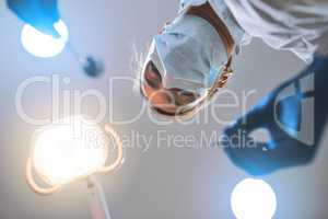 Just remain calm and Ill do the rest. Low angle shot of a focused young female dentist wearing a surgical mask while attempting to work on a patients teeth.