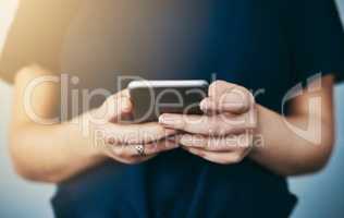 Downloading a new app. Studio shot of an unrecognizable young woman using her cellphone against a grey background.