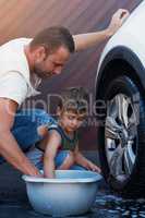 This car is going to be squeaky clean. Shot of a family washing their car in the driveway.