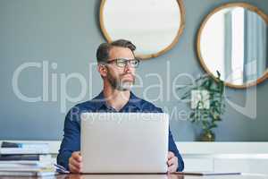 Lets start the day with some work from home. Shot of a confident middle aged businessman working on his laptop while looking into the distance and contemplating at home during the day.