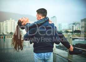 Let love carry you away. Shot of a young man romantically carrying his girlfriend outdoors.