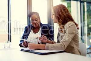 Figuring out their next business move. Shot of two businesswomen working together on a digital tablet in an office.