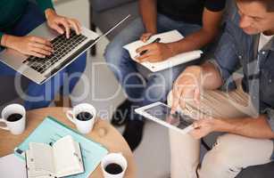 Utilizing tech to make their meetings more efficient. A team of young business professionals using technology in an informal meeting.