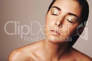 Beauty shines through. Studio shot of a beautiful woman with eyes closed and gold eye makeup.