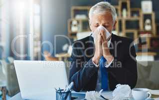 Got to stock up on tissues. Shot of a frustrated businessman using a tissue to sneeze in while being seated in the office.