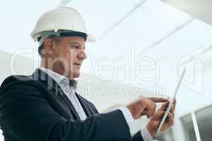 Making some little changes. Shot of a focused professional male architect standing next to a development site while using a digital tablet inside of a building.