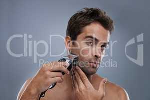 Grooming for the modern man. A young man shaving with an electric razor.