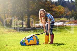 Schools out and summer is here. Portrait of a teenage girl inflating an inflatable ball outdoors.