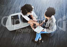 Getting together for another effortless collaboration. High angle shot of two businesswomen working together on a digital tablet in an office.