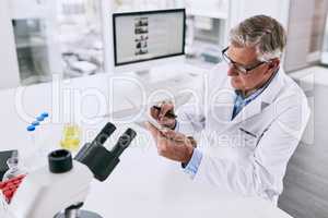 Science and technology depend on each other to make advances. Shot of a mature scientist working on a digital tablet in a lab.