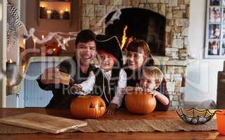These special moments deserve to be captured. Shot of an adorable young family taking selfies together with a cellphone on halloween at home.