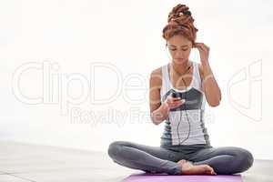 The perfect accompaniment to her yoga session. Shot of a young woman listening to music while practicing yoga outside.