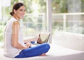 My wifi lets me browse anywhere I want. Shot of an attractive young woman using a laptop while relaxing at home.