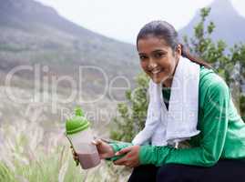 Taking a break from her hike. Portrait of an attractive young woman holding a sports drink outdoors.