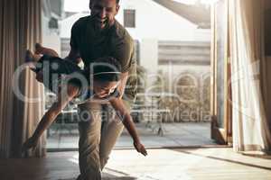 Give them wings and teach them to fly. Shot of a young man enjoying playtime with his daughter at home.