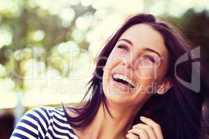 The picture of pure joy. Shot of a beautiful young woman laughing while standing outside.