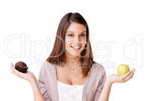 Weighing up the options. Portrait of a beautiful young woman deciding between an apple and a muffin.