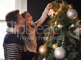 Its a daddy daughter thing. Shot of a young girl and her father decorating the Christmas tree together.