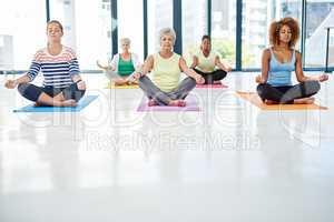Exercise for the mind and body. Shot of a group of women meditating indoors.