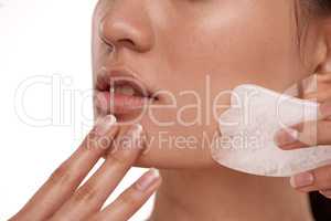 For smoother, firmer skin. Shot of a beautiful woman using a Gua Sha tool on her face.