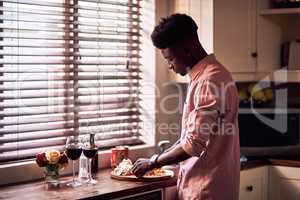 Hes going to spoil his lady today. Cropped shot of handsome romantic young man preparing a meal on Valentines day at home.