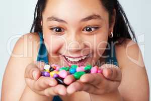 My precious. Studio shot of a cute young girl holding a handful of colorful jelly beans.