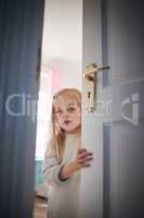 Knock knock, whos there. Shot of an adorable little girl opening a door at home.
