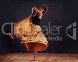 Earth dance. Female contemporary dancer in a dramatic pose against dark background.