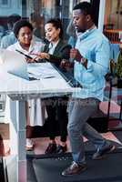 Getting all their creative juices flowing. Shot of a businessman walking on treadmill while having a meeting with his colleagues in an office.