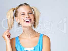 Flirtatious moves. Portrait of attractive young blonde in pigtails playing with her hair.