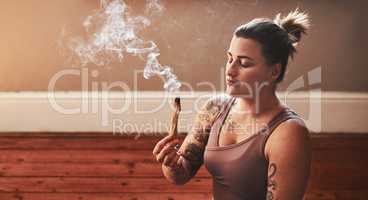 It helps to enhance clarity .and concentration. Shot of a young woman burning a palo santo stick at home.