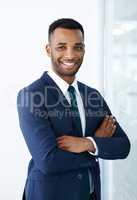 Confident corporate charm. A handsome young african american businessman standing indoors with his arms folded.