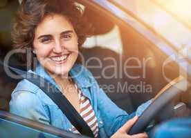Lets go for a drive. Portrait of a happy young woman driving a car.