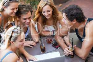 Look at this. Group of teens enjoying beverages while at an outdoor restaurant with all their modern technology.