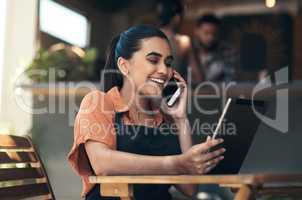 Of course we make large pizzas. Shot of an attractive young woman sitting outside her restaurant and using technology to take orders.