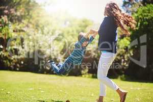 Weeeee. Shot of a mother playfully swinging her son around at the park.
