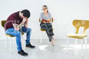 Lifes tough, therapy helps. Shot of a young man having a therapeutic session with a psychologist and looking upset.