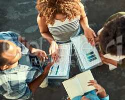 These charts are giving very accurate information. High angle shot of a group of young work colleagues brainstorming ideas together while being seated in the floor of the office at work.