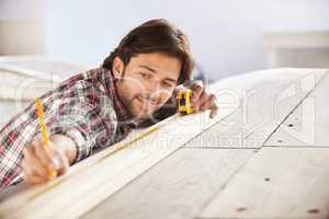 Perfect. A handsome young carpenter measuring and marking wood.