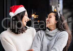 I will honor Christmas in my heart, and try to keep it all the year. Shot of two friends using a sparkle stick ay home.