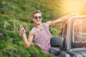 Take it easy wherever you go. Portrait of a young man leaning out the window of a car while on a roadtrip.