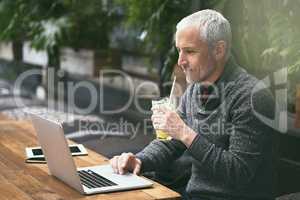 Its his favourite place to work. Shot of a mature businessman using his laptop in a cafe.