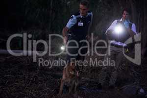 Theyll get their man. Shot of two policemen and their canine tracking a suspect through the brush at night.