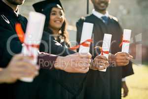 The key to unlocking a rewarding future. Closeup shot of a group of unrecognizable students holding their diplomas on graduation day.