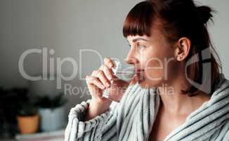 Hydration is a priority to her. Cropped shot of an attractive young woman drinking water in her bedroom at home.