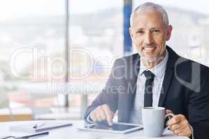 Stay determined and you will prosper. Portrait of a mature businessman working on a digital tablet in an office.