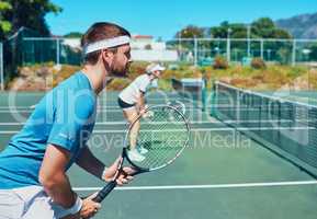 Train like a champion if you want to become one. Cropped shot of a handsome young male tennis player playing together with a female teammate outdoors on a court.